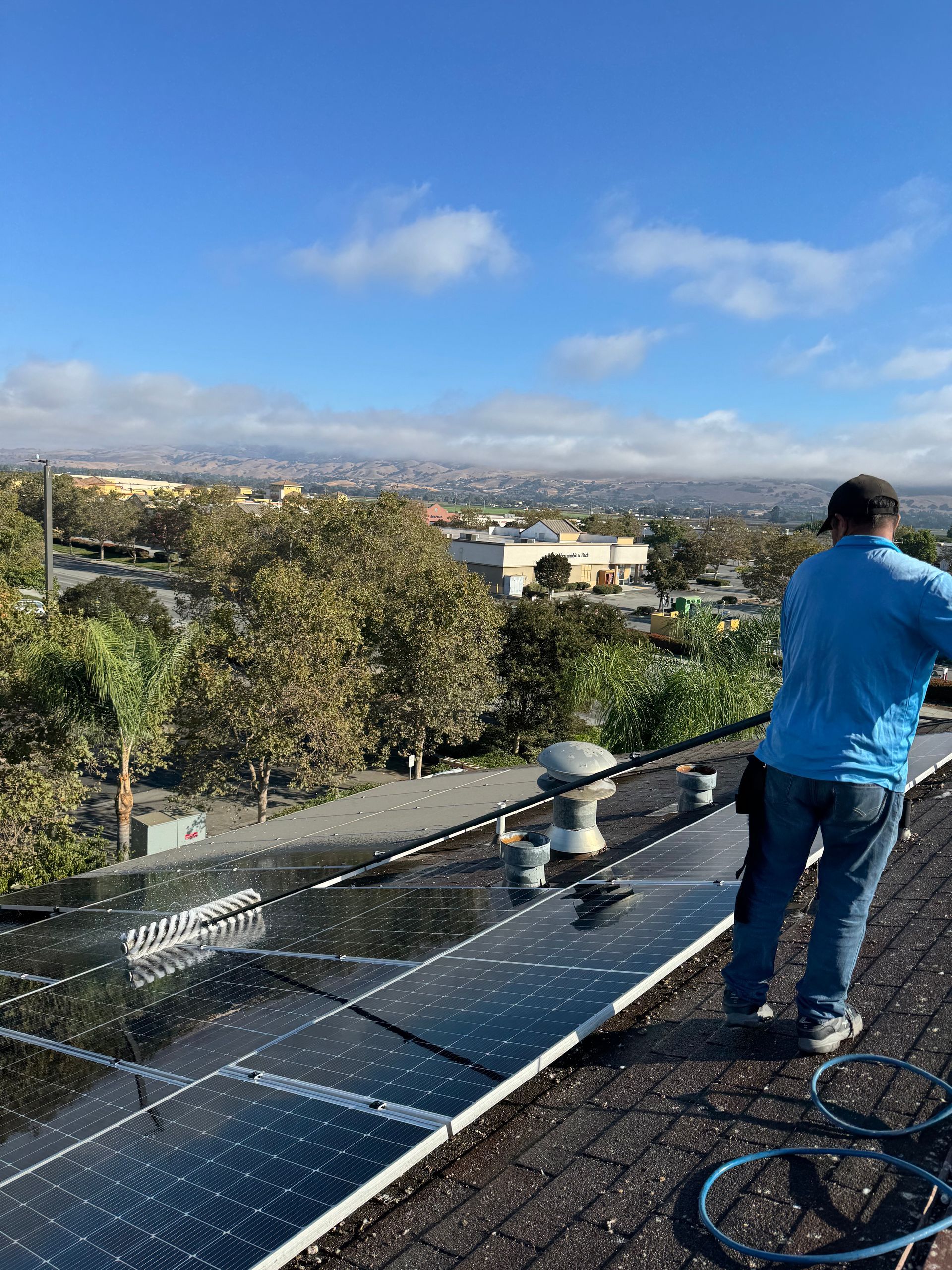 Technician cleaning solar panels on a commercial-style rooftop